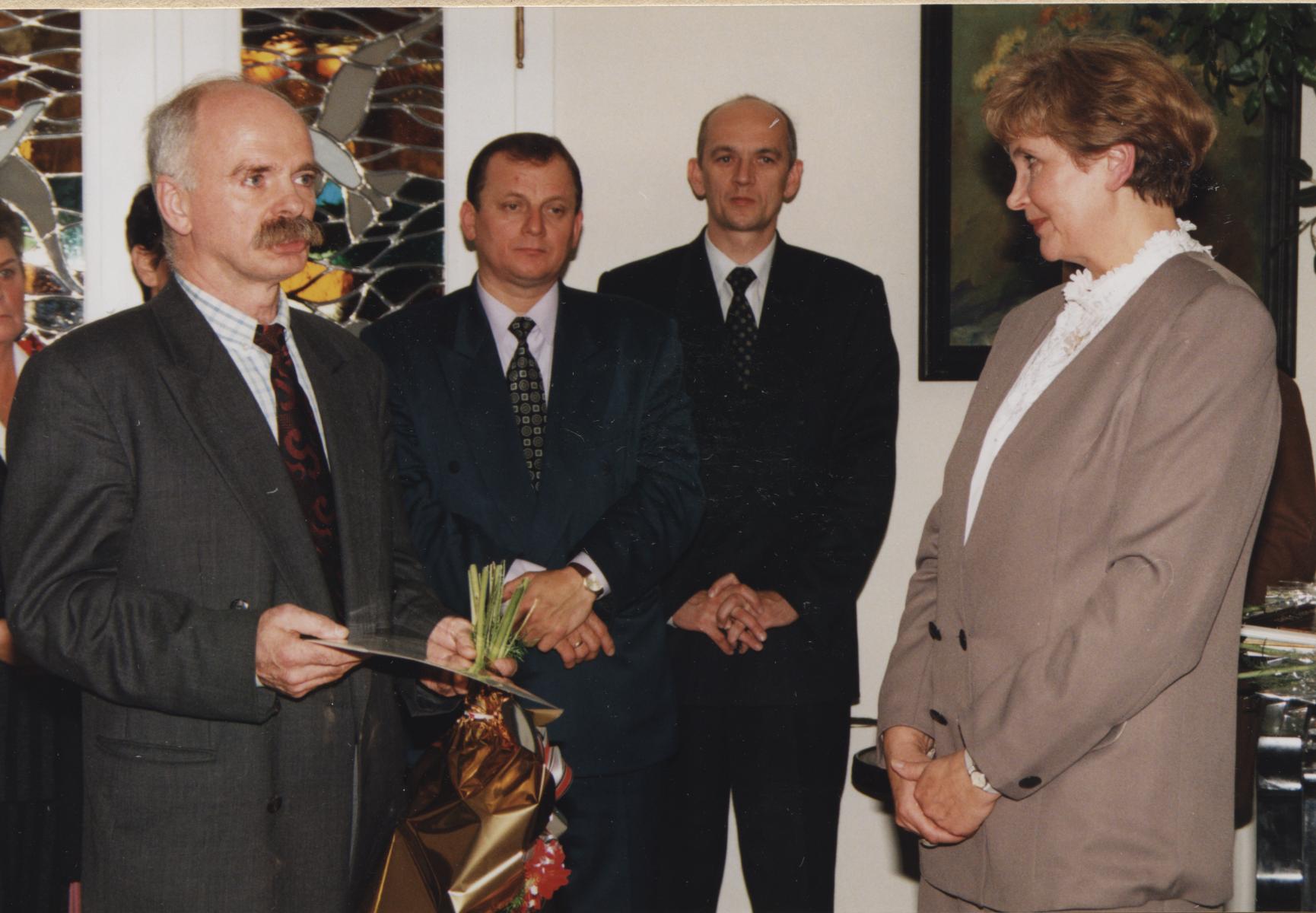 z lewej strony mężczyzna z bukietem kwiatów, z prawej kobieta - dyrektor Muzeum, w tle stoją panowie Prezydent i zastępca Prezydenta Miasta Rybnika.